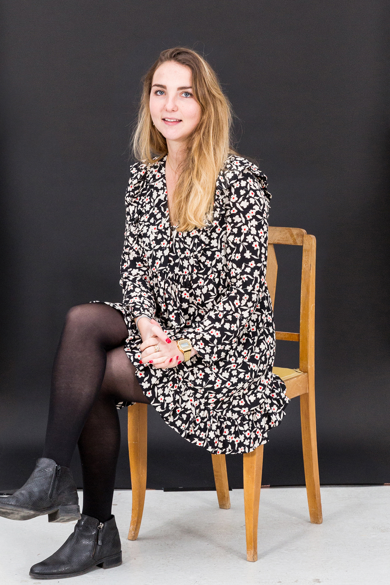 Portrait d'une collaboratrice sur un fond noir assis sur une chaise