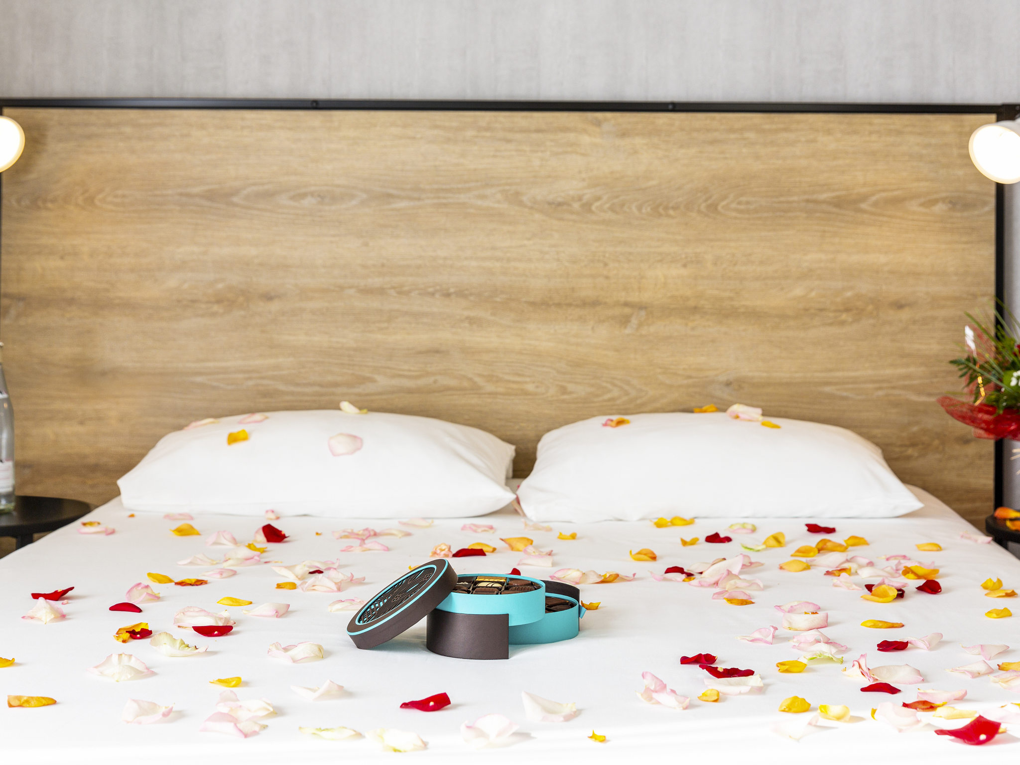 Photographie montrant le lit avec des pétales de fleurs pour une chambre romantique.