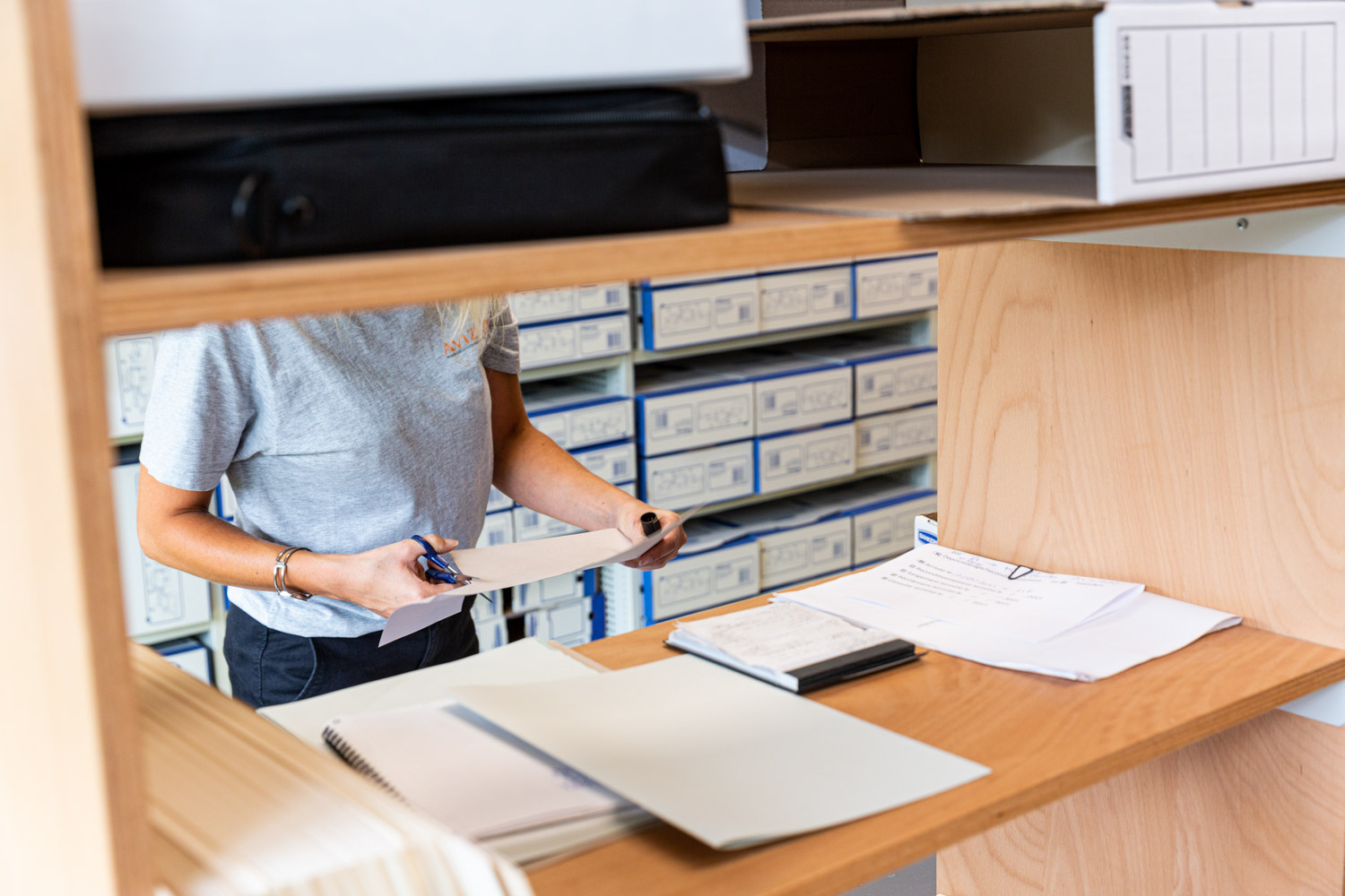 Une personne tri des documents avant des les places dans une boite d'archivage.